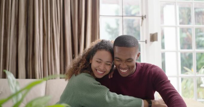 Couple on sofa near French doors, woman showing dark card while man processing purchase on laptop