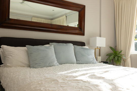 Bed with textured white duvet is anchoring room, blue-gray pillows are resting near lamp and window