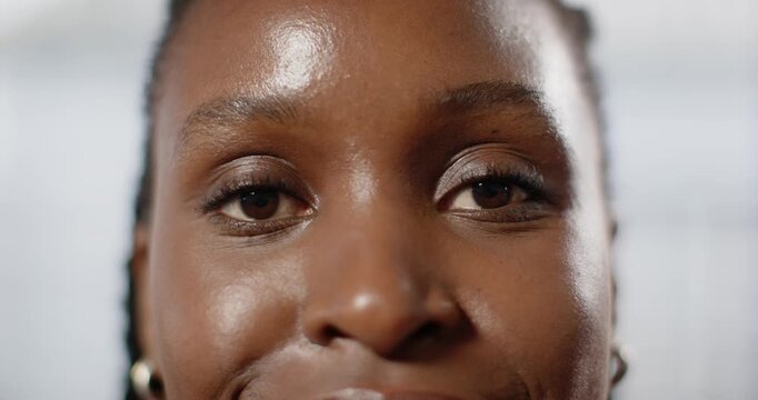 African American woman holding gaze, blinking and shifting to smile during studio shoot with hoops