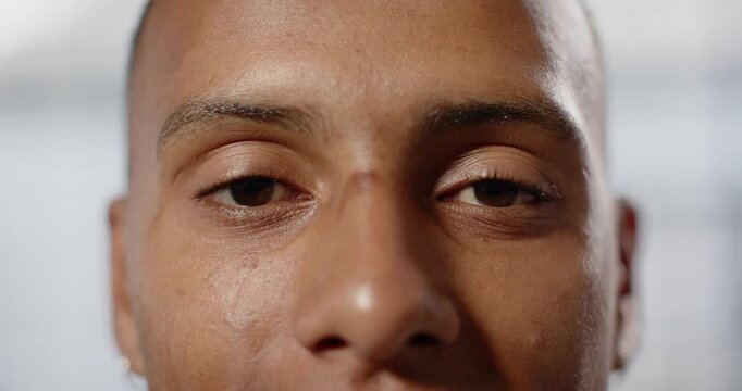 Adult African American man blinking, opening eyes from closed gaze and focusing on camera in studio