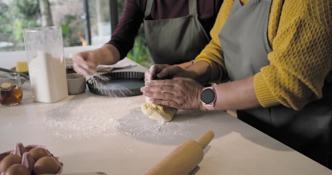 Diverse women senior watching starting dough kneading rolling with pin kitchen island preparing pie