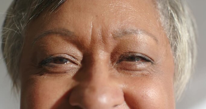 Senior African American woman squinting and smiling, responding to bright left light in room