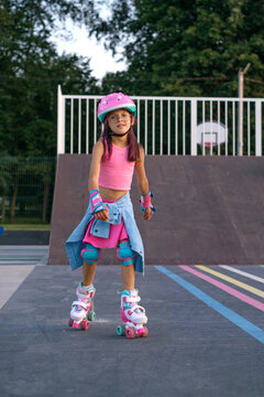 A girl on roller skates squares riding in a skate park. Full protective sports equipment for child safety