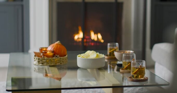 Fireplace flames flickering, camera drifting, glare shifting on glass table with chips and candles