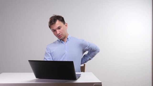 Man experiences severe lower back pain and discomfort while sitting with poor ergonomics, highlighting the health risks of a sedentary lifestyle and long hours working from home