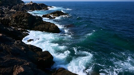 Fototapeta premium A calm rocky coastline is captured with dynamic spray swirling foam and striking light on the water