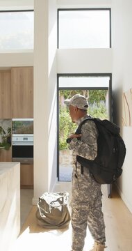 Vertical video: African American man in camo returning home carrying pack and duffel, settling