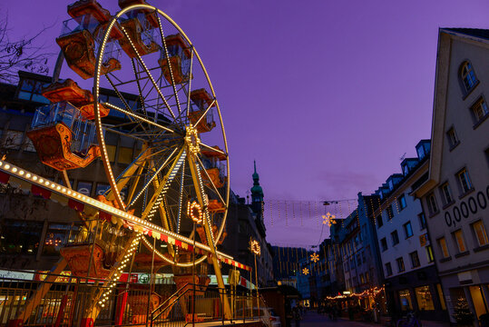 Beleuchtetes Riesenrad auf dem Weihnachtsmarkt in Bregenz vor violettem Abendhimmel am Bodensee