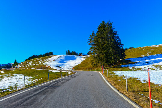 Bergfahrt auf der Jaunpassstrasse mit Schneeresten auf den Bergwiesen unter strahlend blauem Himmel