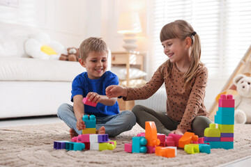 Naklejka premium Little kids playing with colorful blocks on floor at home