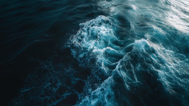 Horizontal high angle view of dark blue ocean water with crashing waves and white seafoam spray