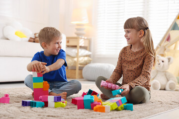 Obraz premium Little kids playing with colorful blocks on floor at home
