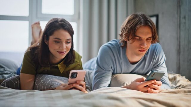 Indifferent couple looking phones lying bed closeup. Boyfriend girlfriend online