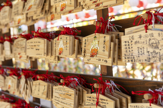 View of traditional wooden prayer plaques known as ema hanging on a rack at a shinto shrine with red strings and handwritten wishes Osaka, Osaka, Japan.
