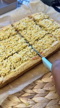 Step by step process of making homemade strawberry jam crumble bars cutting the baked pastry into squares close up
