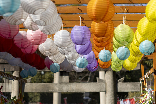 View of colorful paper lanterns hanging from a wooden structure at a traditional shrine in Osaka, Osaka, Japan.