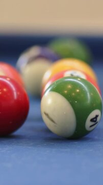 Vertical video: Pulling focus back, green 14 ball rotating on blue felt, red ball moving