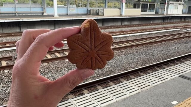 Hand holding Hiroshima's famous cookie, a maple momiji manju, a classic souvenir of Hiroshima Prefecture in Japan,