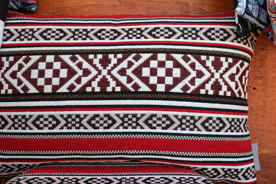 Traditional woven pillow with geometric ethnic patterns and red stripes.
