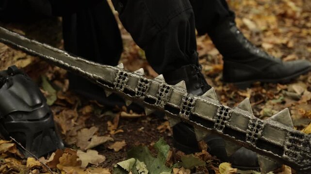 Forest floor, Forest flail, Weapon ground. On forest floor, spiked metal weapon is positioned among fallen leaves, with boots appearing in background.