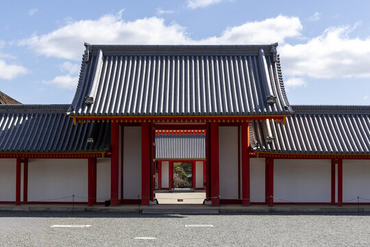 View of the traditional red gate and white walls of the Kyoto Imperial Palace under a blue sky in Kyoto, Kyoto, Japan.