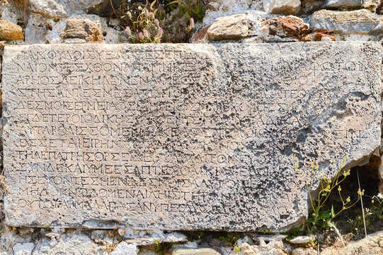Ancient stone inscription from the Roman Empire period embedded in the archaeological ruins of Syedra Ancient City near Alanya, T&uuml;rkiye. Historical carved text on weathered stone monument