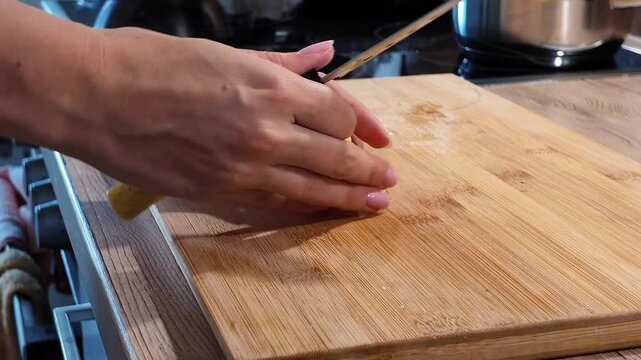 Close-up: slicing a potato into thin slices with a kitchen knife on a cutting board.