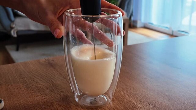 Close-up of white liquid being poured into a container with a smooth