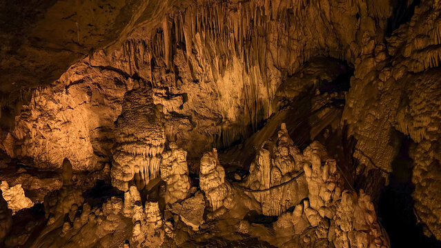 Illuminated karst cave with stalactites lit by amber light creates dramatic mood suitable for travel editorial, tourism and nature education, 5 May 2026 Subitica, Serbia