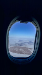 Fototapeta premium Airplane window view over frozen river and snowy plains in crisp blue light suitable for travel blogs editorial social media winter content, serene, 5 May 2026 Subitica, Serbia