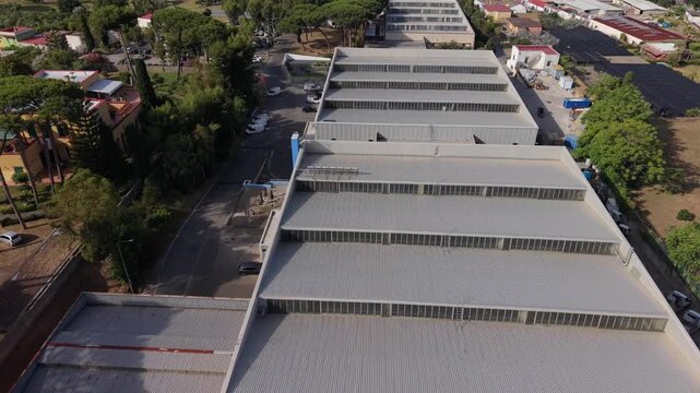 Aerial view of industrial warehouse complex with greenhouses surrounded by pine trees in Torre del Greco coastal area, Naples, Italy