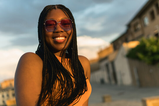 Smiling black woman enjoying golden hour city sunset