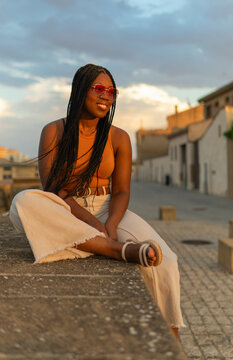 Young woman enjoying urban sunset wearing sunglasses