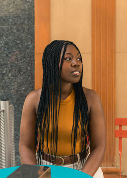 Young black woman sitting outdoors looking away