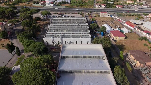 Aerial view of large industrial warehouse buildings with metal roofs and highway in Torre del Greco urban industrial zone, Naples, Italy
