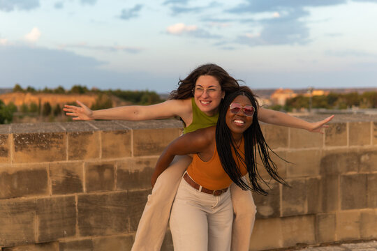 Happy young women enjoying piggyback ride outdoors
