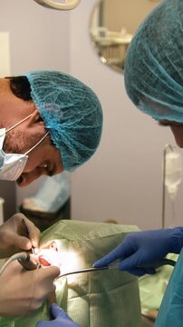 Dentist using surgical pliers to remove a decaying tooth in stomatology room