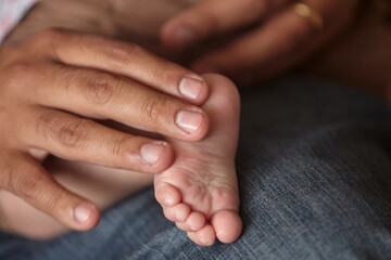 Fototapeta premium A father's strong, sun-weathered grip, wearing a leather watch strap that marks the passage of ordinary time, cradles the tiny, perfect foot of his newborn daughter with extraordinary tenderness.