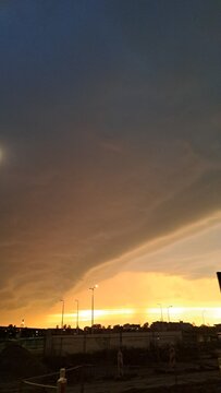 Massive Arcus Shelf Cloud at Sunset Featuring Dramatic Storm Front, Golden Horizon Light, Atmospheric Weather Phenomenon, Urban Skyline Silhouettes and Extreme Sky Photography Concepts

