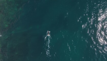 Obraz premium Aerial view of a person surfing on a surfboard in the deep blue ocean