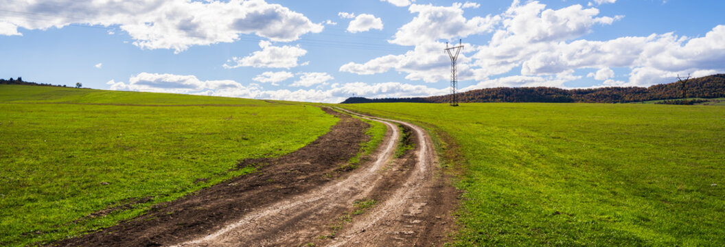 Country road leading into vast valley and greenery, peaceful travel route through natural landscape.