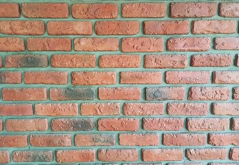 Fototapeta premium A premium full-frame texture photograph of a contemporary red brick wall featuring a distinctive lime green mortar finish. This vibrant, high-contrast masonry surface brings a bold, modern twist to cl
