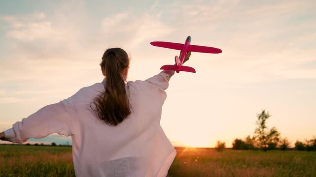 Little girl become pilot fly, travel. Happy kid runs with toy airplane field in rays sun. Child plays with toy airplane. Child aviator dreams flying becoming pilot. Slow motion. Family picnic outdoors