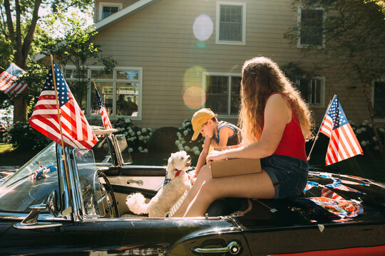 girl and boy sitting in car with american flag