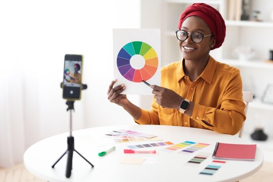 Smiling Black Woman Holding Color Wheel While Presenting Ideas And Working Creatively At Home Office. Engaged In Color Theory And Design Process, Focused On Professional Workspace.