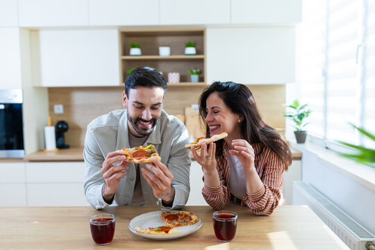 Couple enjoys pizza and drinks in a kitchen