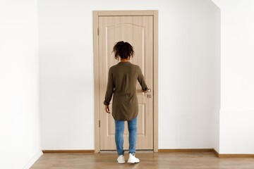 Fototapeta premium Unrecognizable Female Opening Door In Modern Home Setting, Wearing Casual Attire, Standing In Front Of Doorway. Inspiring Casual Environment For Home Living And Interior Designs.