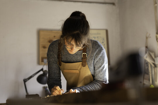 View of a woman wearing an apron working on a piece of wood in a workshop in Lisbon, Lisbon, Portugal.
