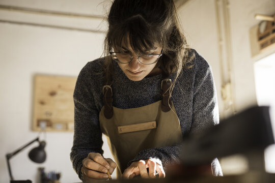 View of a focused woman wearing an apron and glasses working on a craft project in a workshop in Lisbon, Lisbon, Portugal.