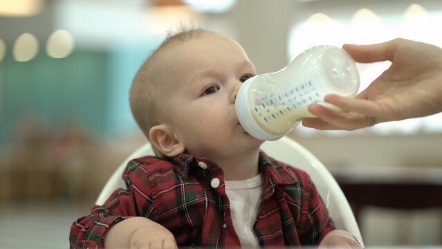 Mom feeds her toddler baby from a bottle with infant formula